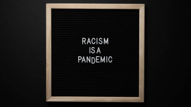 White letters against a black backdrop spell out the words "Racism is a pandemic"